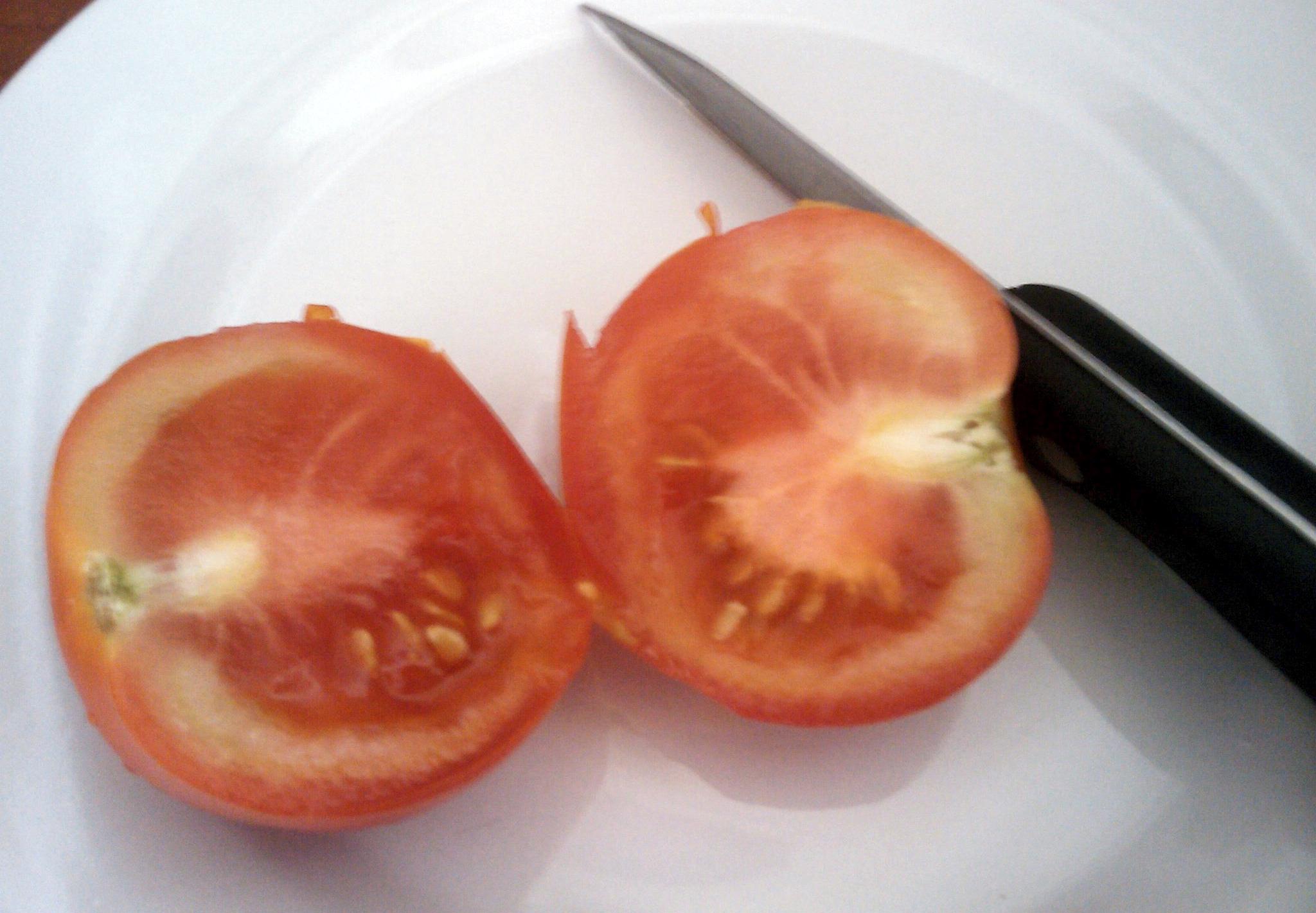 Red tomato cut in half with knife