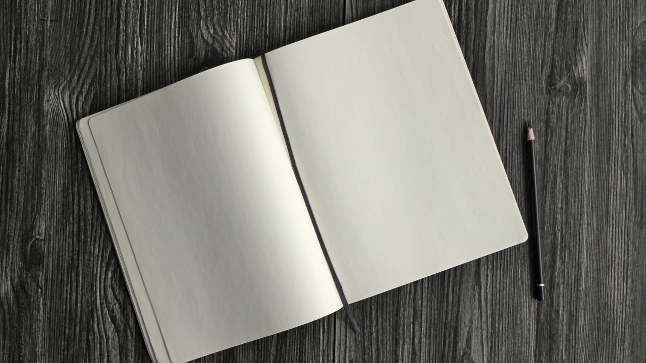 A notebook of white paper and a pencil on a block desk