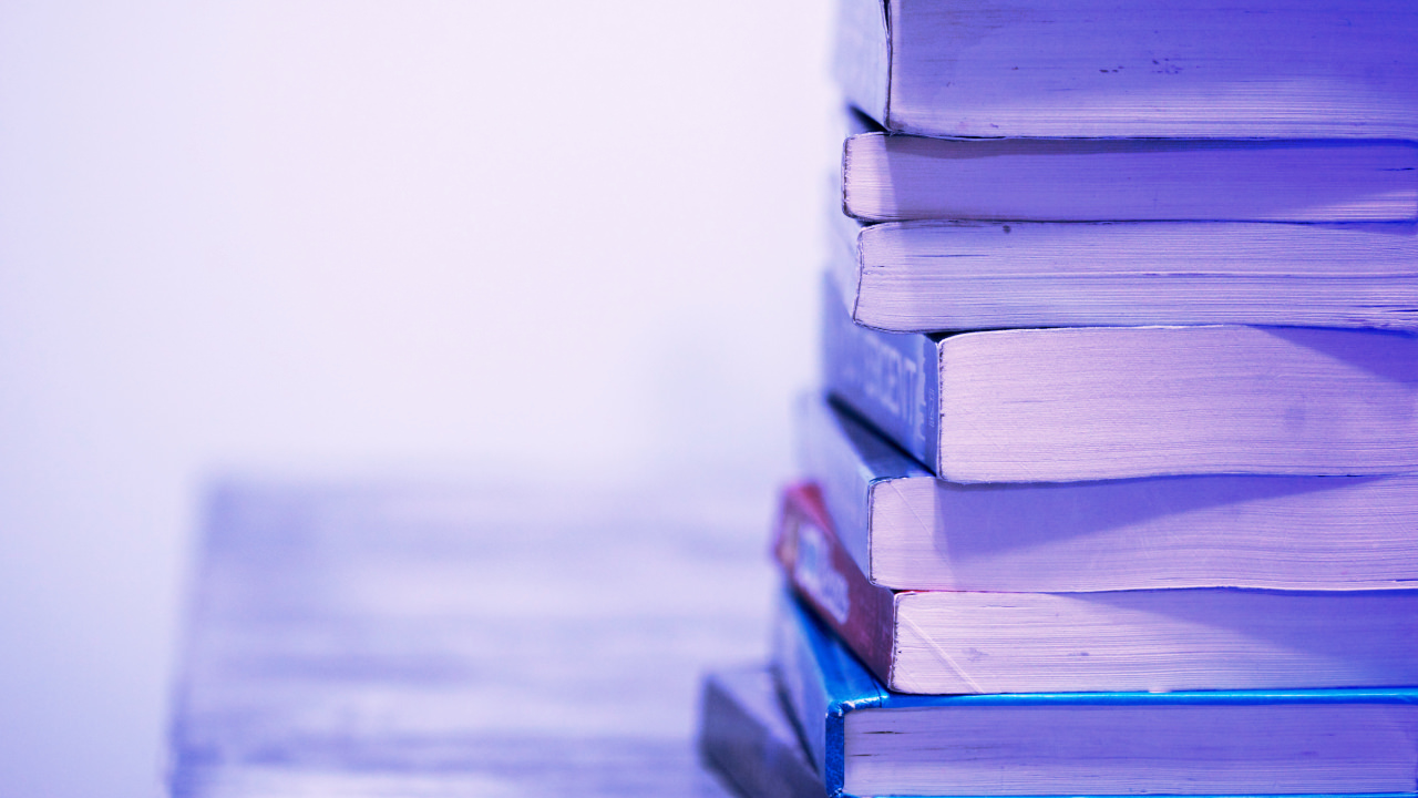 A pile of books end on to the right of the picture, blank space to the left, all with a blue gradient over the top