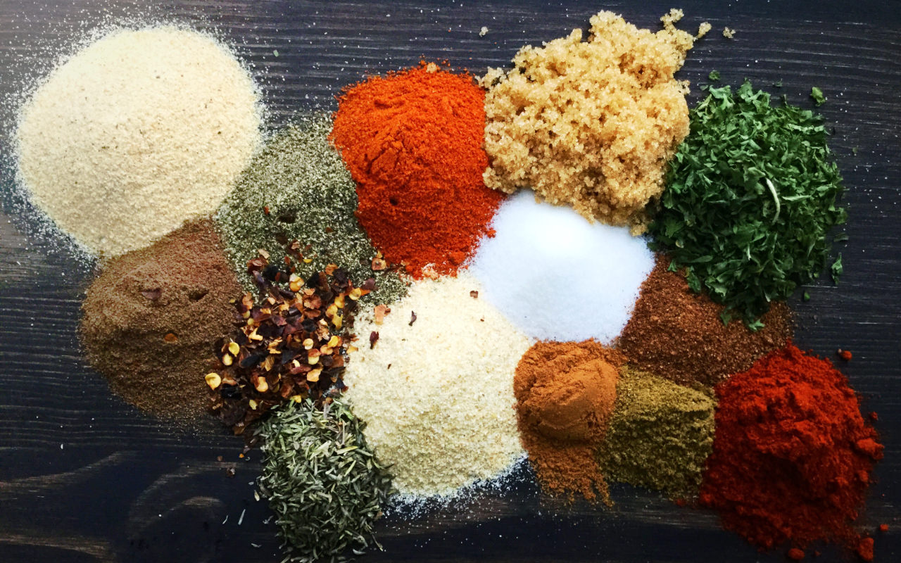 A selection of spices and seasonings piled on a wooden surface