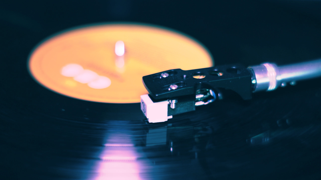 A close up of a vinyl record with the needle of the record player sitting on top