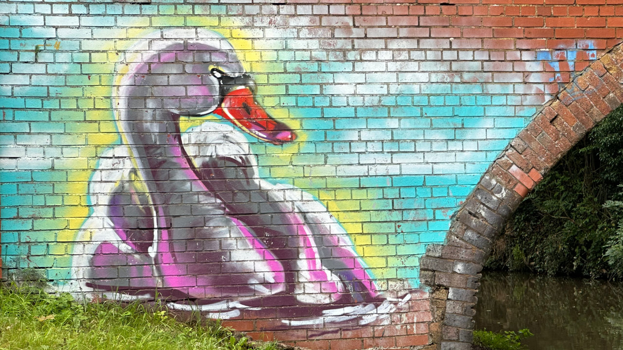 A canal bridge wall with the bricks spray-painted with the image of a swan