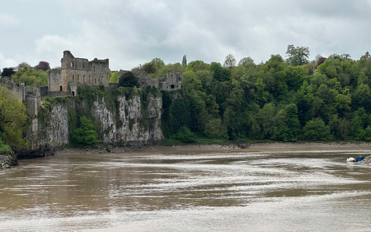 A photo of the ruins of Chepstow Castle, perched on cliffs overlooking the muddy river