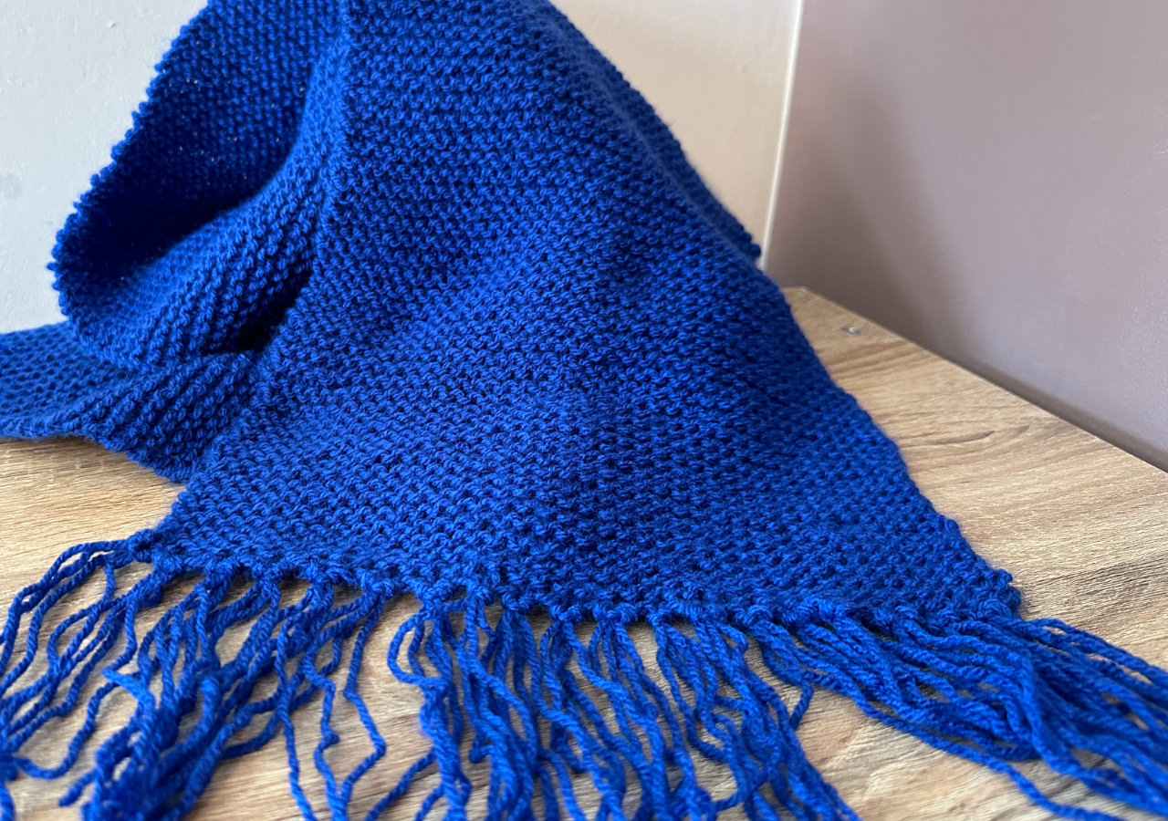 A photograph of a blue knitted scarf