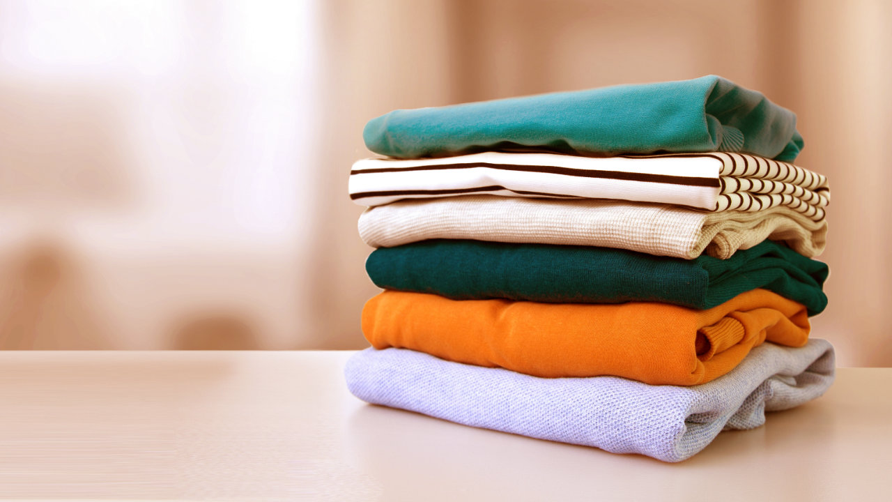 A stack of folded clothes to the right of the image sitting on a countertop
