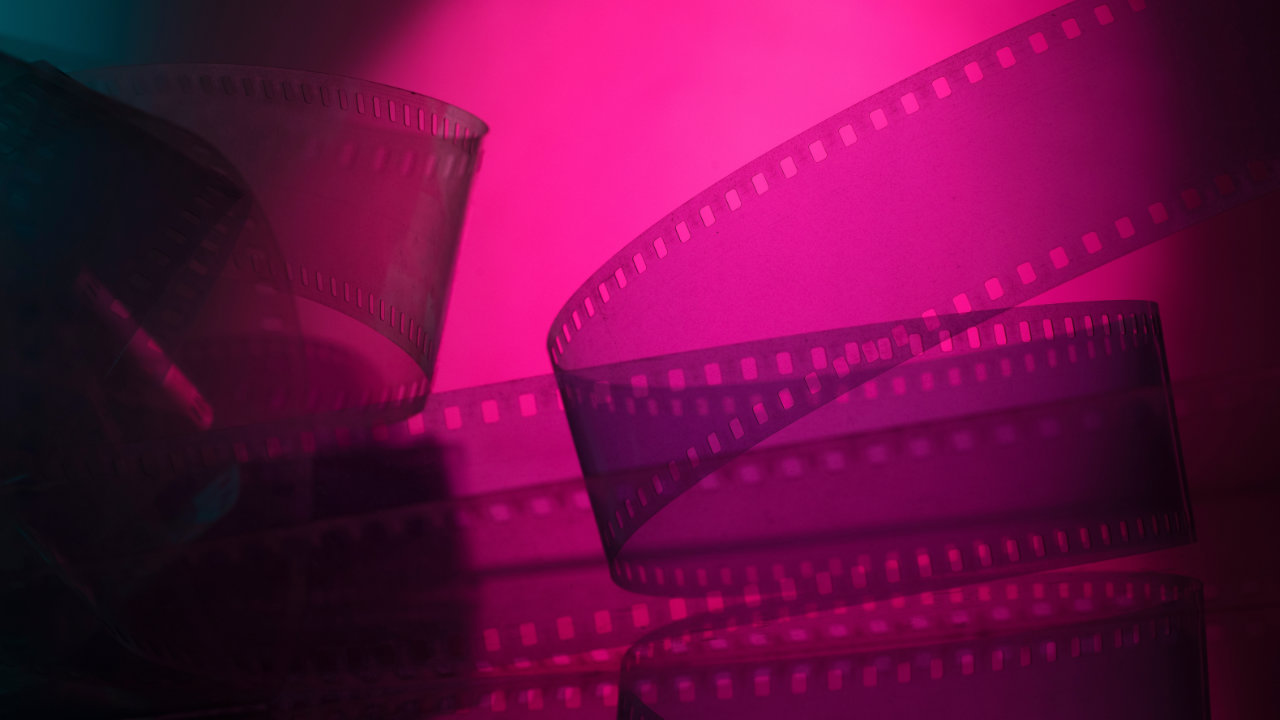 Rolls of film unspooling on a pink illuminated background