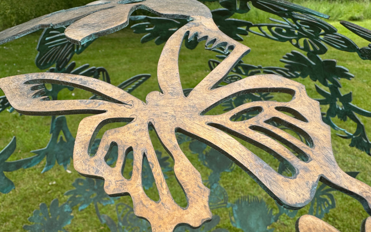 A close up of a spherical garden sculpture featuring cut out designs including this, a butterfly