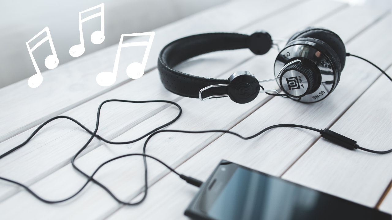 A high end pair of headphones, plugged in to a phone, with three sets of musical notes in white overlaid in the top left