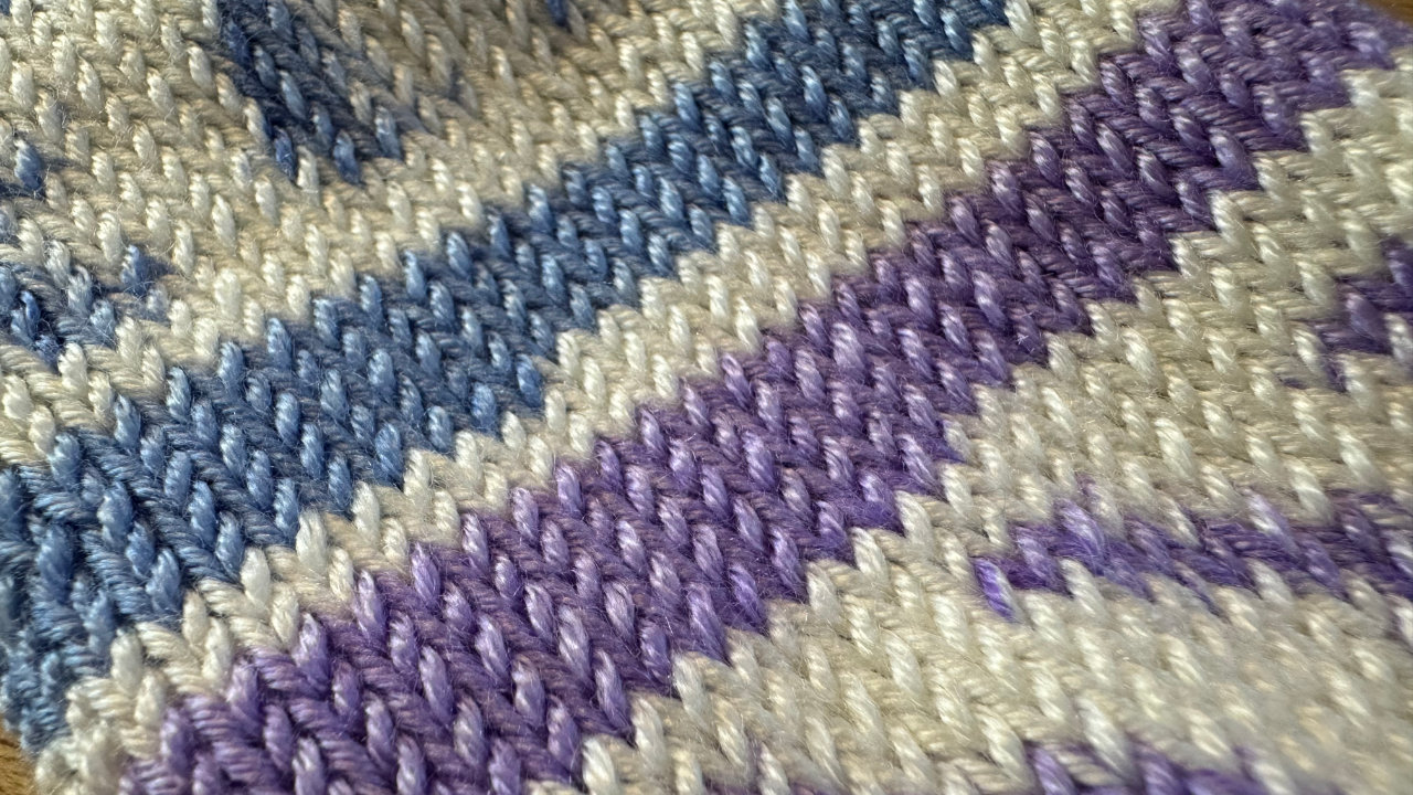 A close up of the knitted sock showing nice neat rows of various colours of yarn