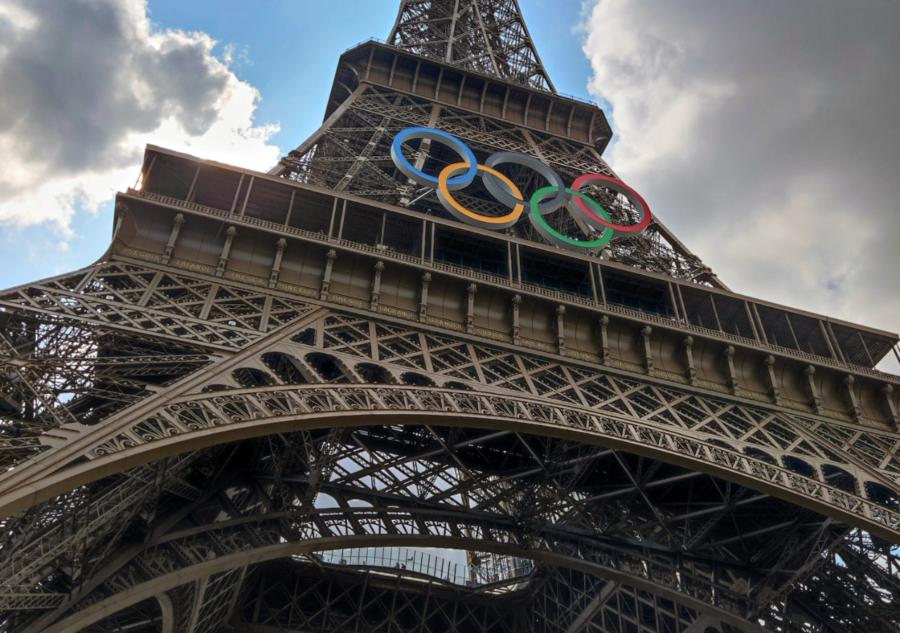 Looking up at the middle section of the Eiffel Tower with the Olympic Rings affixed to the ironwork