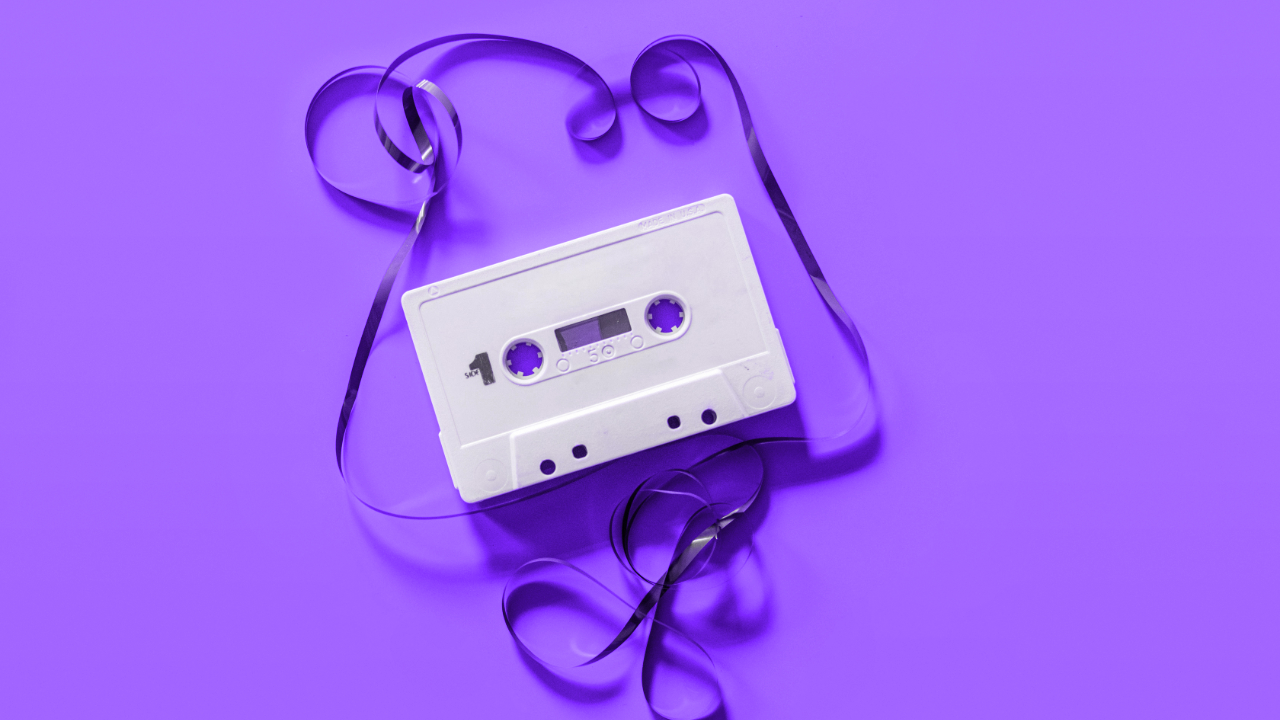 A purple background with a cassette tape in the middle, the tape pulled out from the cassette and curling around the image