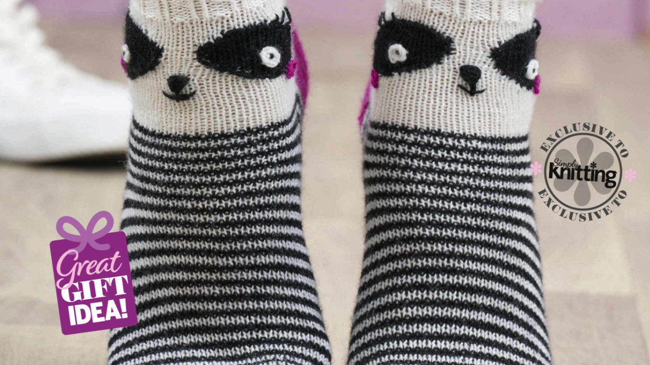 A close up of some feet wearing knitted panda socks, featuring two black and white eyes above the ankle, and the rest of the sock striped black and white
