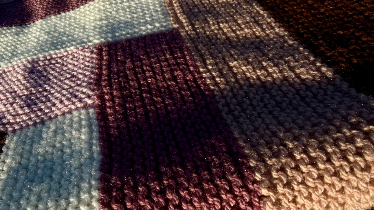A close up of the blanket showing the knitted stitches and the stripes fitting together