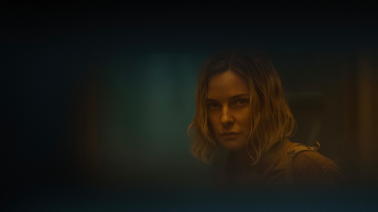 A still from the second series of Silo, featuring Rebecca Ferguson as Juliette Nichols looking through a small window in a door