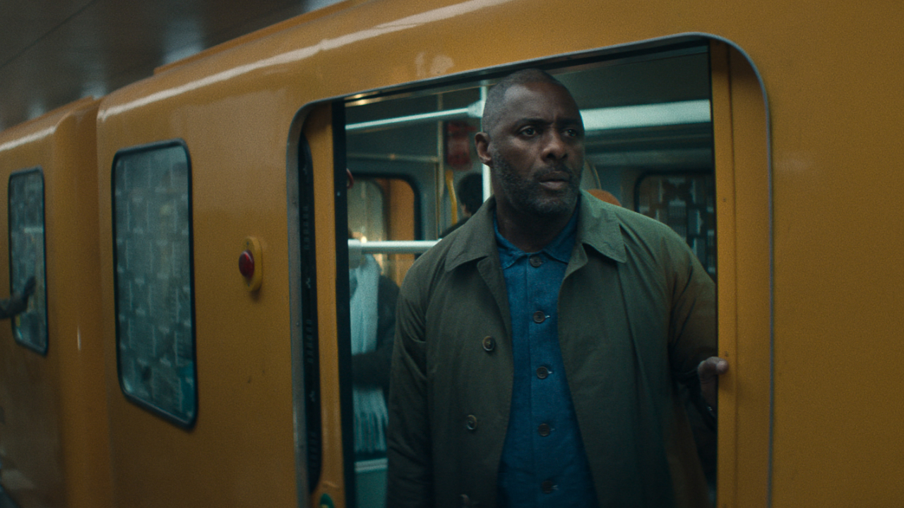 A still from the Apple TV show Hijack featuring main character Sam played by Idris Elba stepping off a yellow subway train